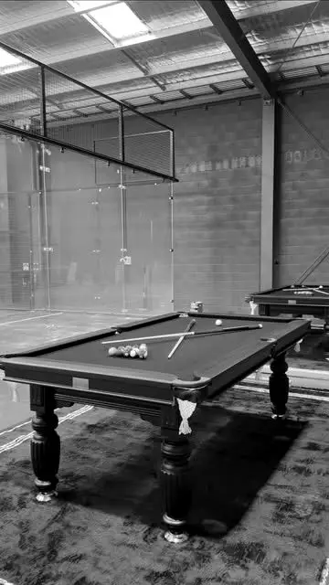 A pool table set up inside the venue, the padel court behind it.