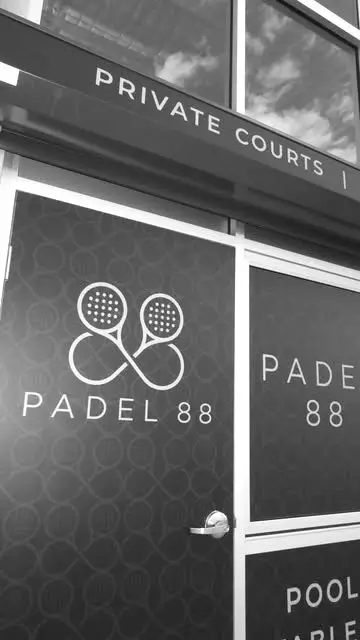 The Padel 88 crossed-racquet monogram and wordmark on the venue wall.
