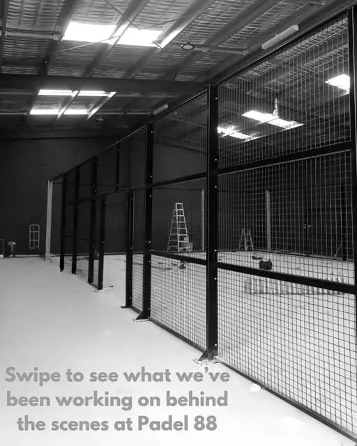 The court mid-construction, mesh fencing going up and a ladder against the frame.